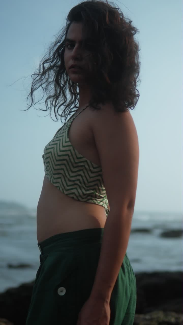 Woman in a patterned halter swimsuit with wind blowing in her hair under a clear sky, vertical shot
