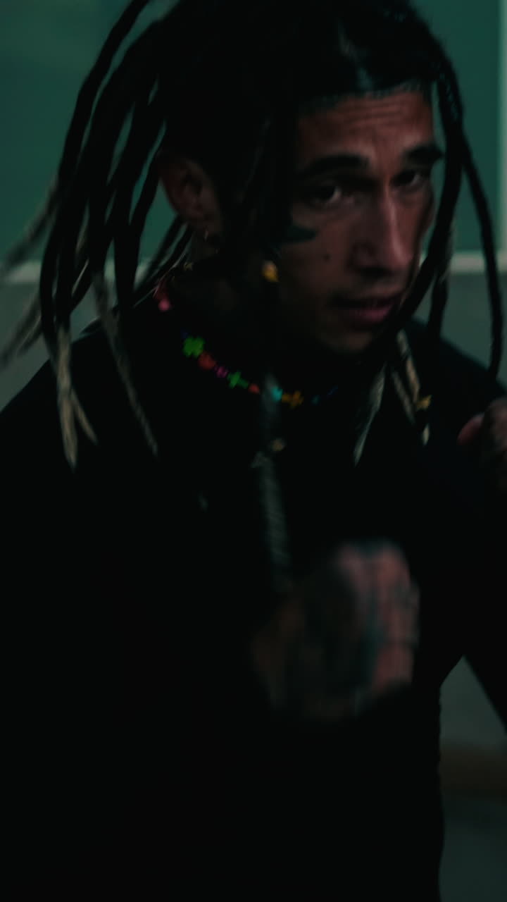 Giovane uomo espressivo con dreadlocks e tatuaggi che si muove energicamente