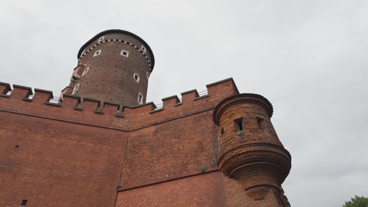 Historic brick Sandomierska Tower at Wawel Castle in Krakow seen from a low angle under a cloudy sky