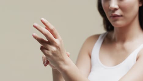 Hands-of-asian-woman-with-dark-hair-on-beige-background,-slow-motion