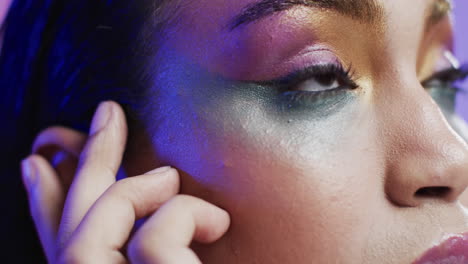 biracial woman with black hair and make up touching her face, copy space, slow motion