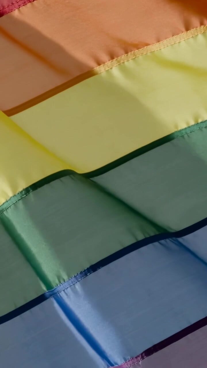 Vertical video: Rainbow flag shifting and rippling after soft motion, revealing seams for design