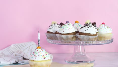 blowing birthday candle on sweet cup cake served on the table for party