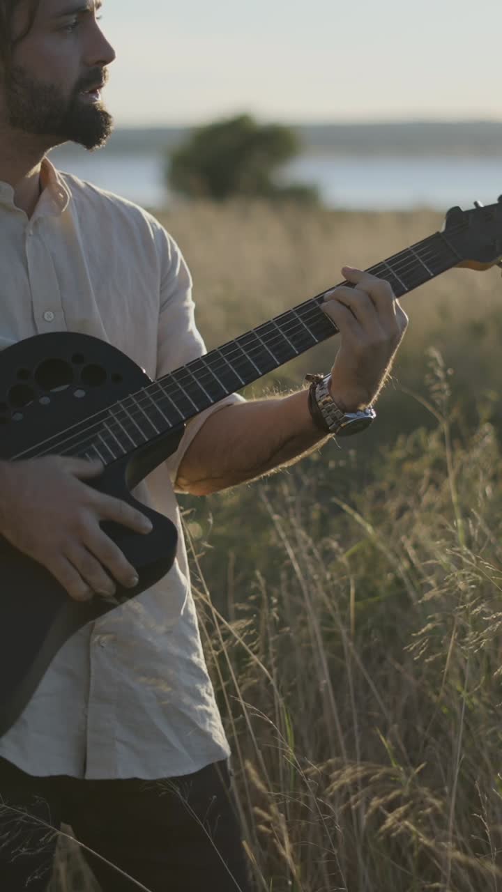 Mężczyzna grający na gitarze na złocistym polu trawiastym