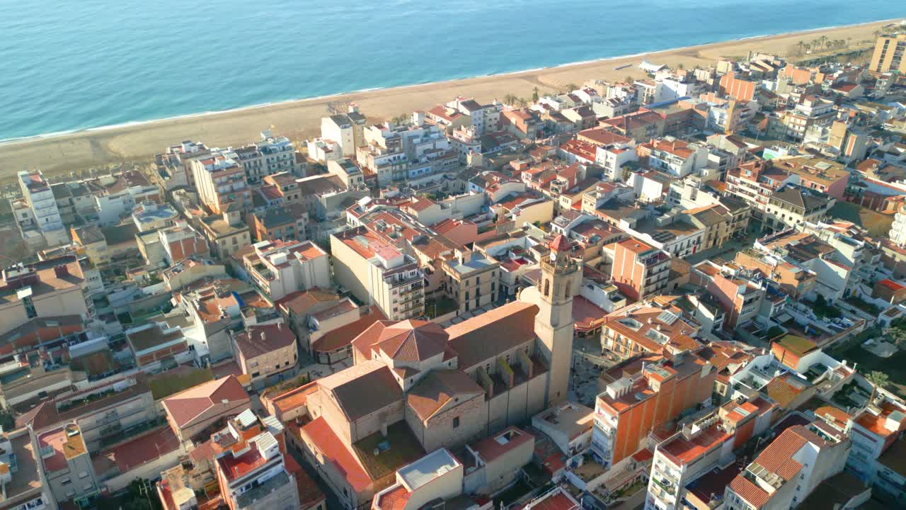 Aerial view highlighting the historic calella de mar cathedral, surrounded by vibrant town structures and coastline. Captures the charm of spain's coastal architecture