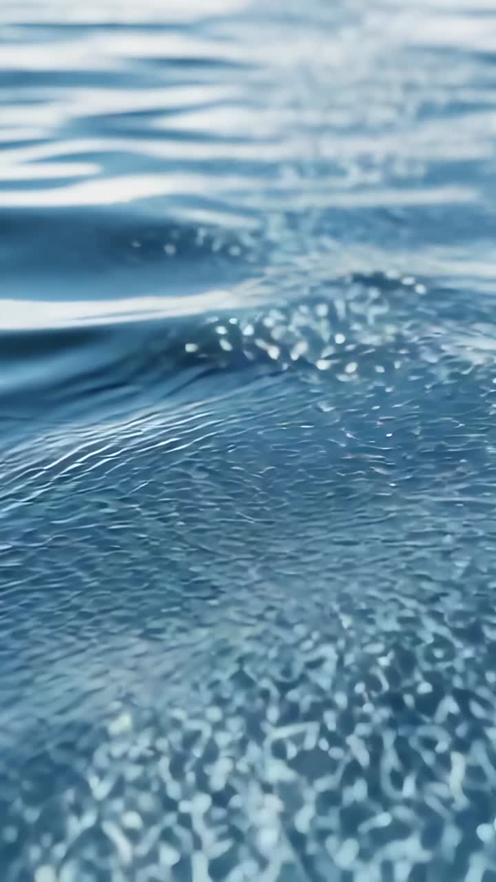 Video verticale: increspature dell'acqua che si muovono, stimolando pennacchi di bolle in mare e spargendo riflessi luminosi