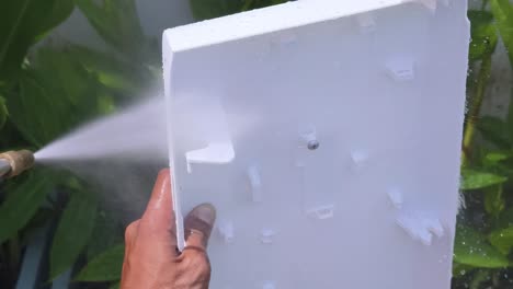 cleaning a white plastic panel with a pressure washer