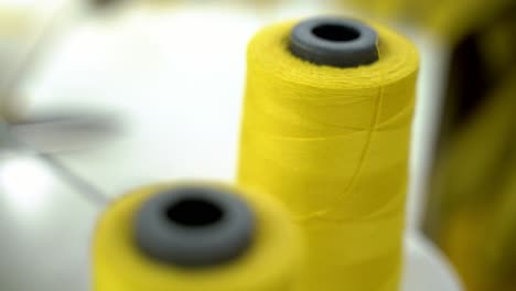 Closeup-Shot-Of-Yellow-Cotton-Thread-On-A-Spool-In-Sweatshop