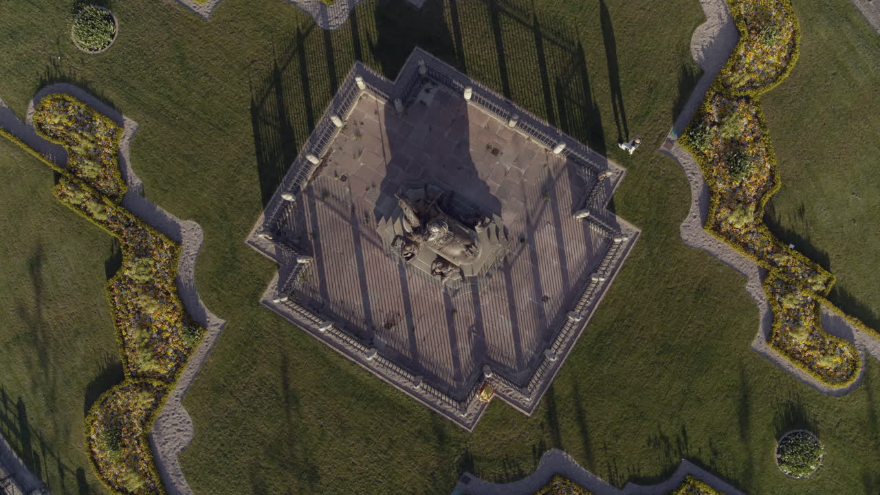 imágenes de drones que giran lentamente de arriba hacia abajo sobre un hombre que camina alrededor de una estatua en medio de kings square copenhague al amanecer