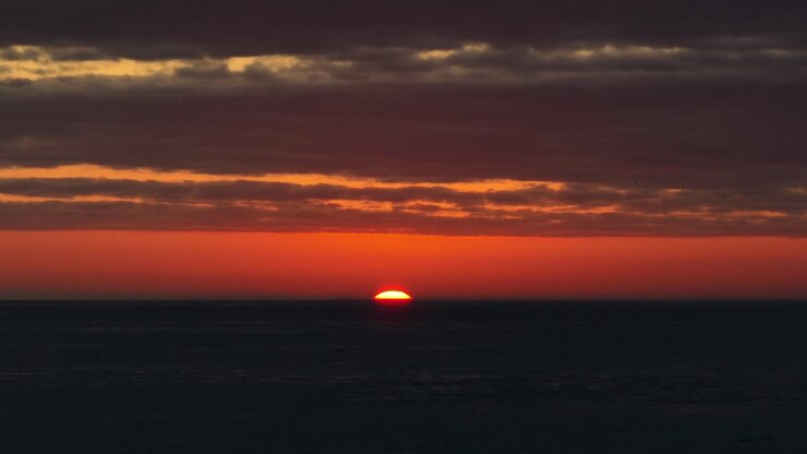 Static shot of the vibrant sun setting over the horizon slowly in Iquique, Chile