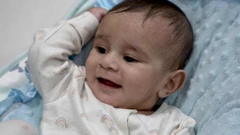 Six-Month-Old-British-Asian-Baby-Being-Expressive-And-Smiling-In-Basket-displaying-curiosity-and-relaxation