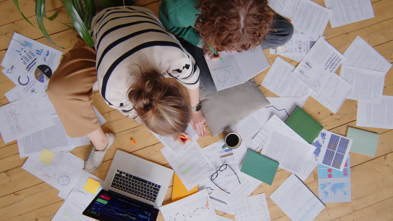 Two Female Freelancers Working with Papers and Laptop