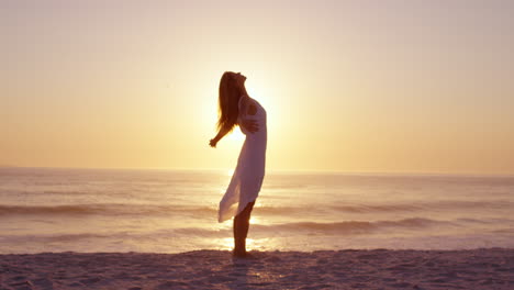 Mujer-Feliz-Libre-Con-Los-Brazos-Extendidos-Disfrutando-De-La-Naturaleza-En-La-Playa-Al-Atardecer-Con-La-Cara-Levantada-Hacia-El-Cielo-En-Cámara-Lenta-Dragón-Rojo