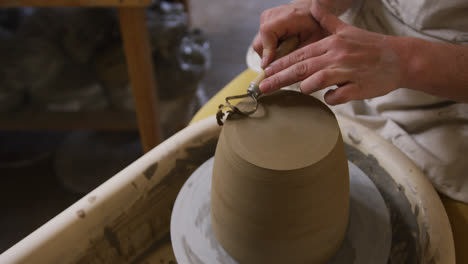 close up view of female potter using loop tool for finishing pottery at pottery studio