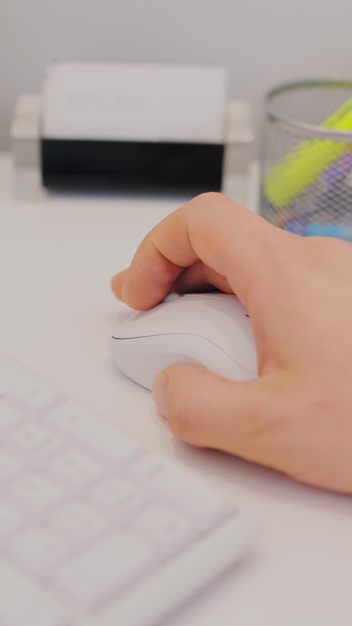 Clean vertical close up of man clicking mouse at modern white desk in office