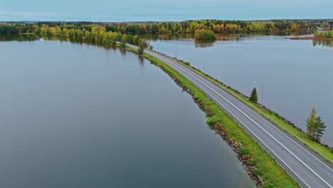 wide shot of a land bridge road highway with cars crossing a lake in valkeakoski, finland