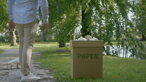 hombre tirando papel en papelera cerca de pájaro blanco, propósito de reciclaje
