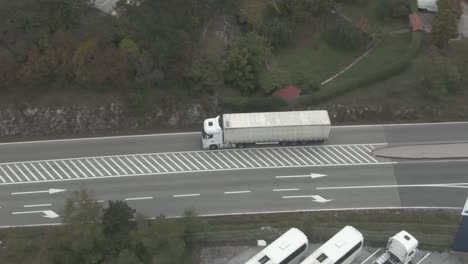 Un-Camión-Con-Remolque-Que-Transporta-Carga-A-Través-De-Una-Ciudad-Al-Lado-De-Algunos-Edificios-De-Apartamentos