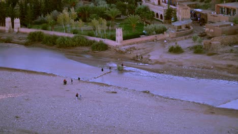 loaded donkey crossing the river oued el maleh near ait ben haddou monument in morocco