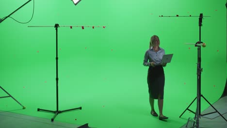 beautiful young woman wearing casual skirt and shirt, using laptop computer in green screen mock up chroma key studio. business, corporate office, work, technology concept.