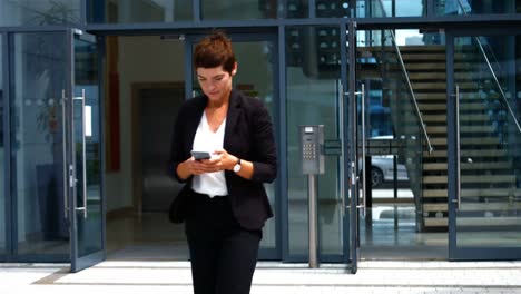 Businesswoman-using-mobile-phone-while-walking