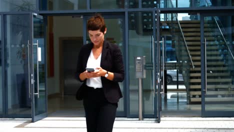 mujer de negocios usando el teléfono móvil mientras camina