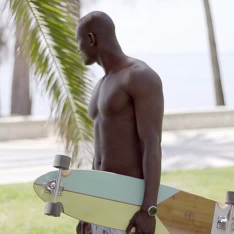 shirtless black skater walking in grassy park