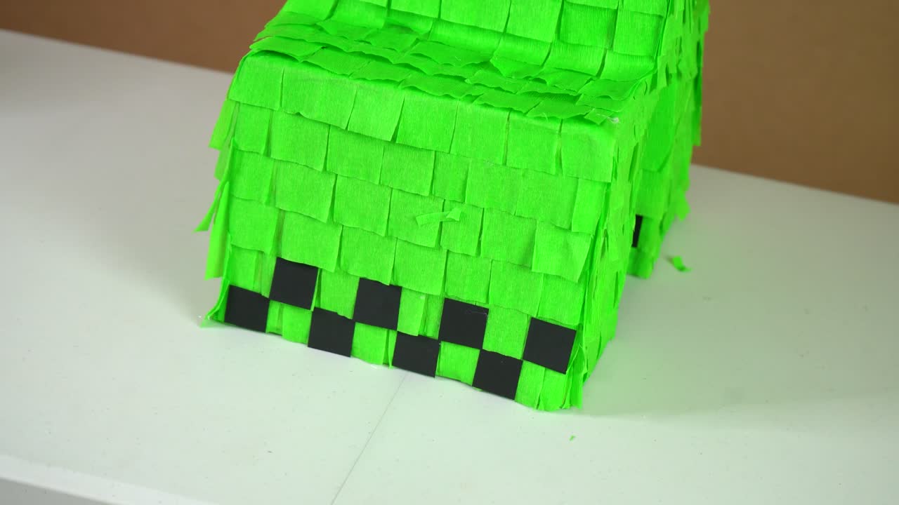 Close-up of green piñata with detailed texture on flat surface