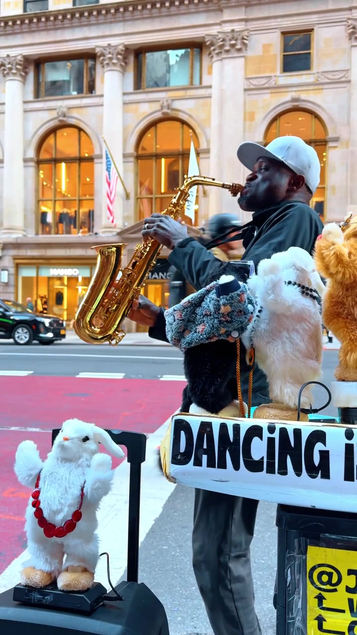 New York, USA, 5. oktober 2025: Nærbillede af gademusiker, der spiller saxofon nær legetøj. Detalje af en mand, der spiller på en gylden saxofon med dansende plyslegetøj i forgrunden.