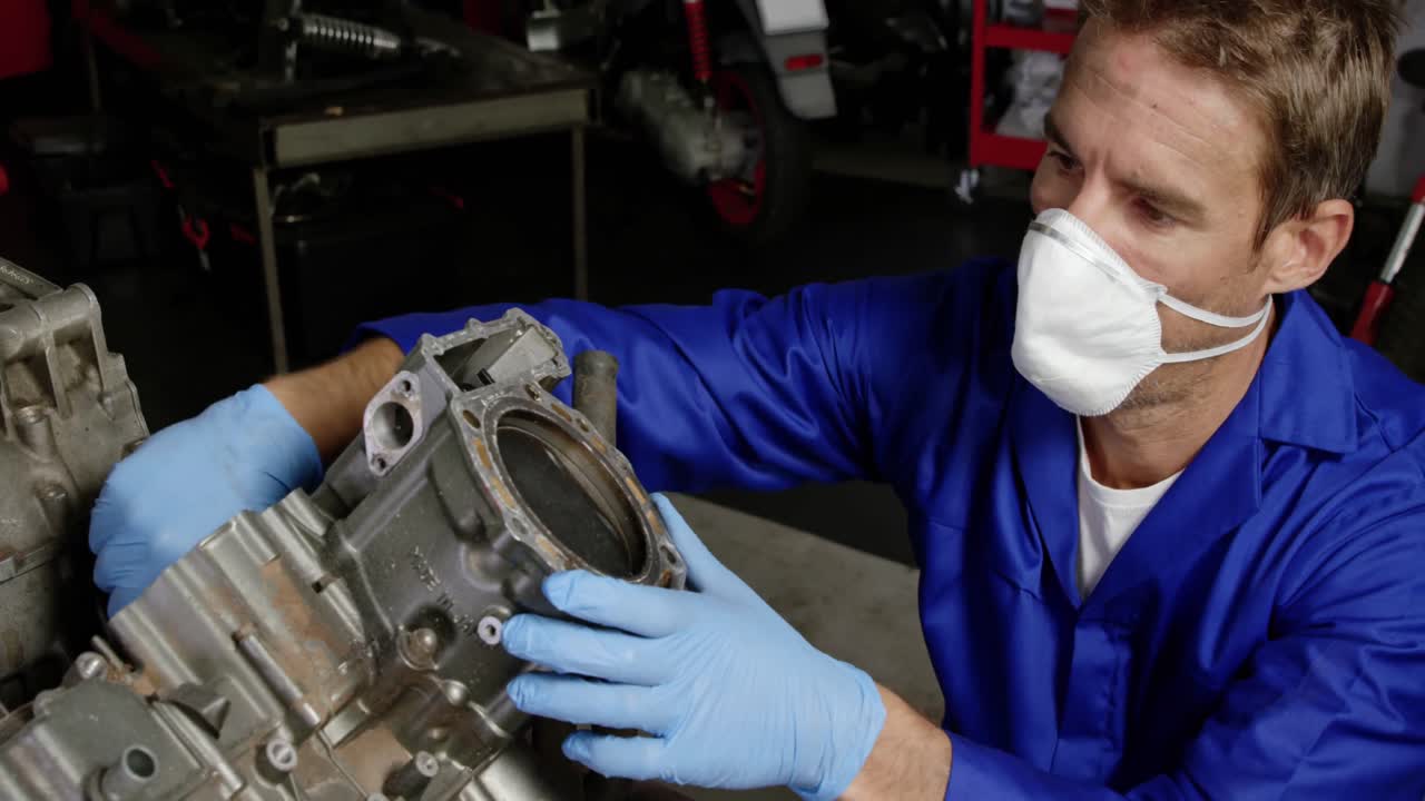 mecánico masculino reparando el motor de una motocicleta en un garaje de reparación 4k