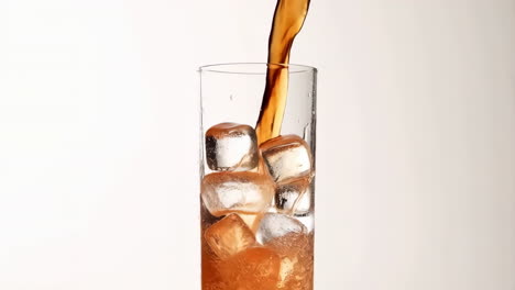 pouring a cold beverage into a glass with ice