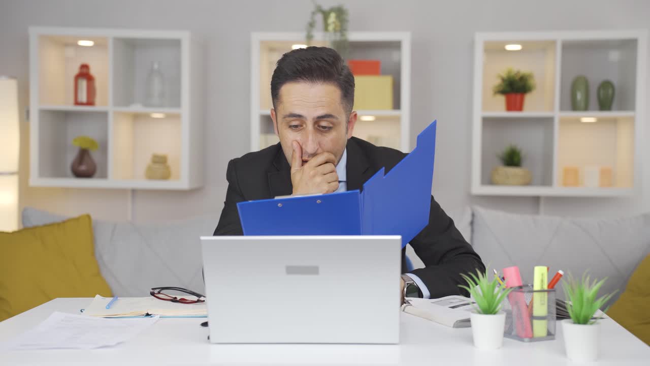 홈 오피스 직원 남자가 분노로 파일을 보고 있습니다.
