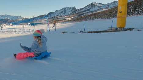 a girl sledding on a snowy mountain slope
