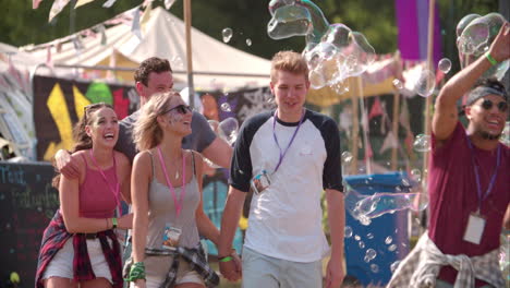 friends walk through bubbles at music festival, slow motion