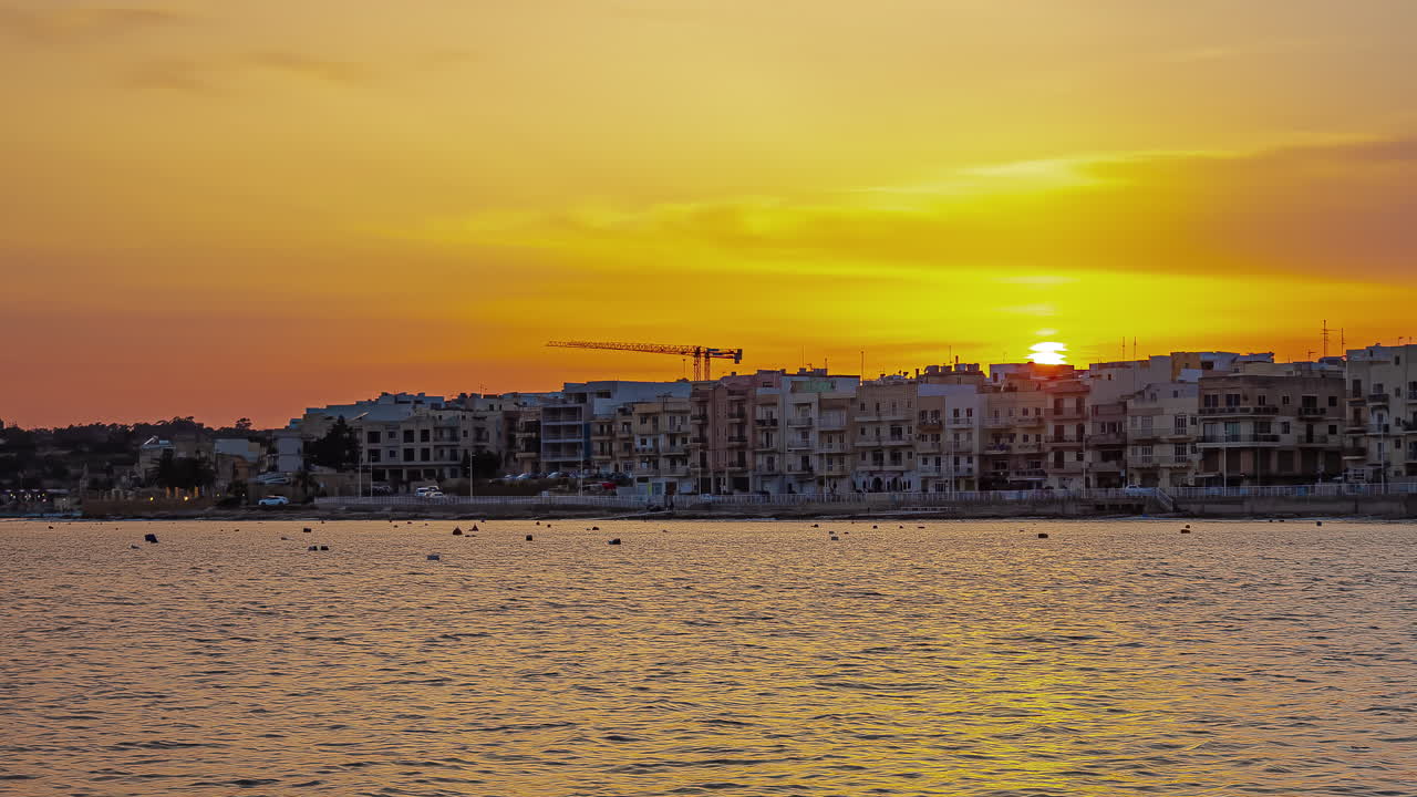 time-lapse de la puesta de sol frente a los edificios frente al mar en gżira en malta