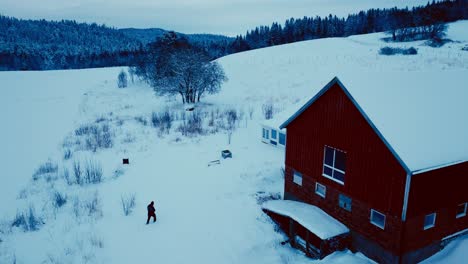 aerial view of a man walking near barn house in winterly landscape