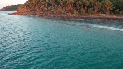 Drone-shot-circling-a-paddleboarder-floaring-by-the-shore,-shot-on-a-Mavic-2-Pro-in-the-late-afternoon