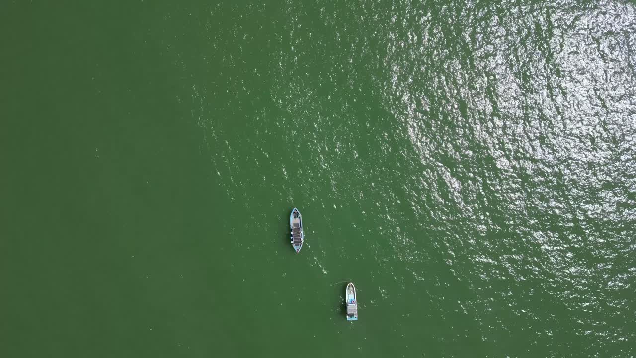 Two fishing boats flying over wide open ocean, top down drone tracking shot