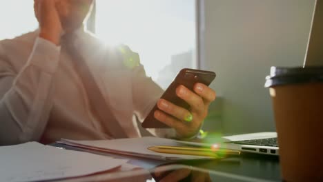 Front-view-of-young-Caucasian-male-executive-working-on-mobile-phone-at-desk-in-modern-office-4k