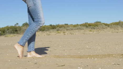 female legs kicking sand at a beach