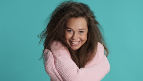 Caucasian-curly-haired-woman-hugging-in-front-of-the-camera.