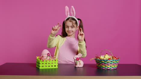 cheery innocent child showing peace sign in studio and wearing bunny ears