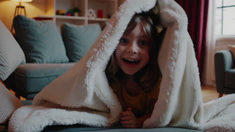 a playful child having fun under a blanket
