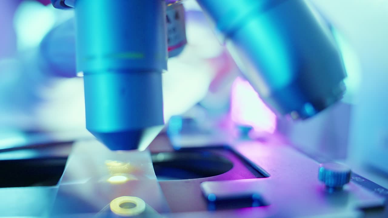 Scientist Placing Sample Slide Under Microscope Lens in Laboratory
