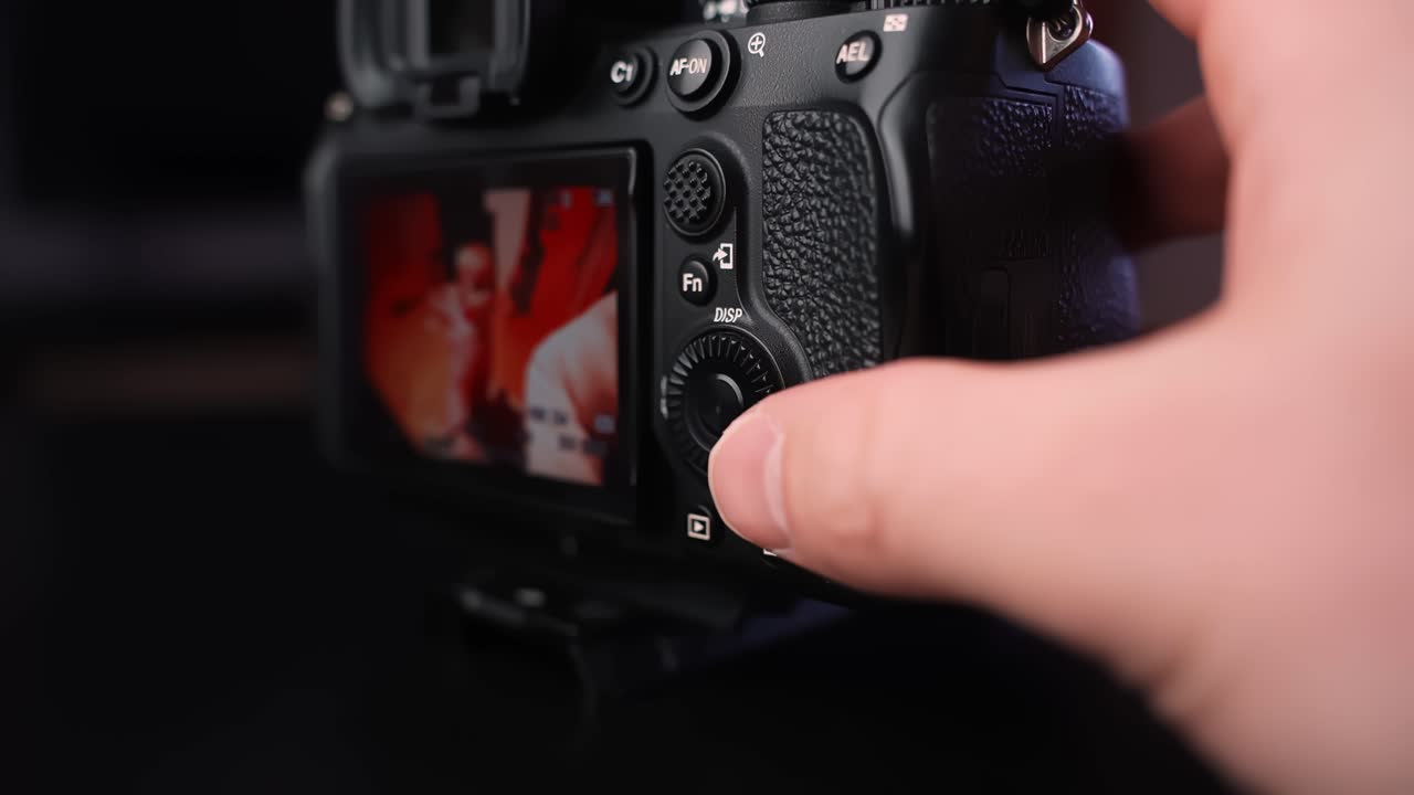 Primo piano di un fotografo che scorre le immagini sul display LCD di una fotocamera mirrorless, revisionando scatti e impostazioni durante il flusso di lavoro di uno shooting in studio.