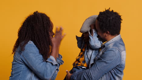 familia afroamericana alegre posando juntos contra un fondo amarillo