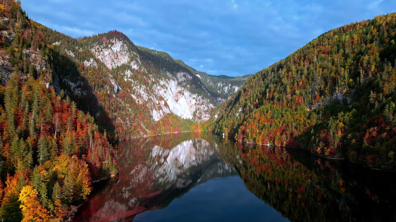 Glacial lake at autumn in Austria's countryside with mountains reflecting off the water - aerial