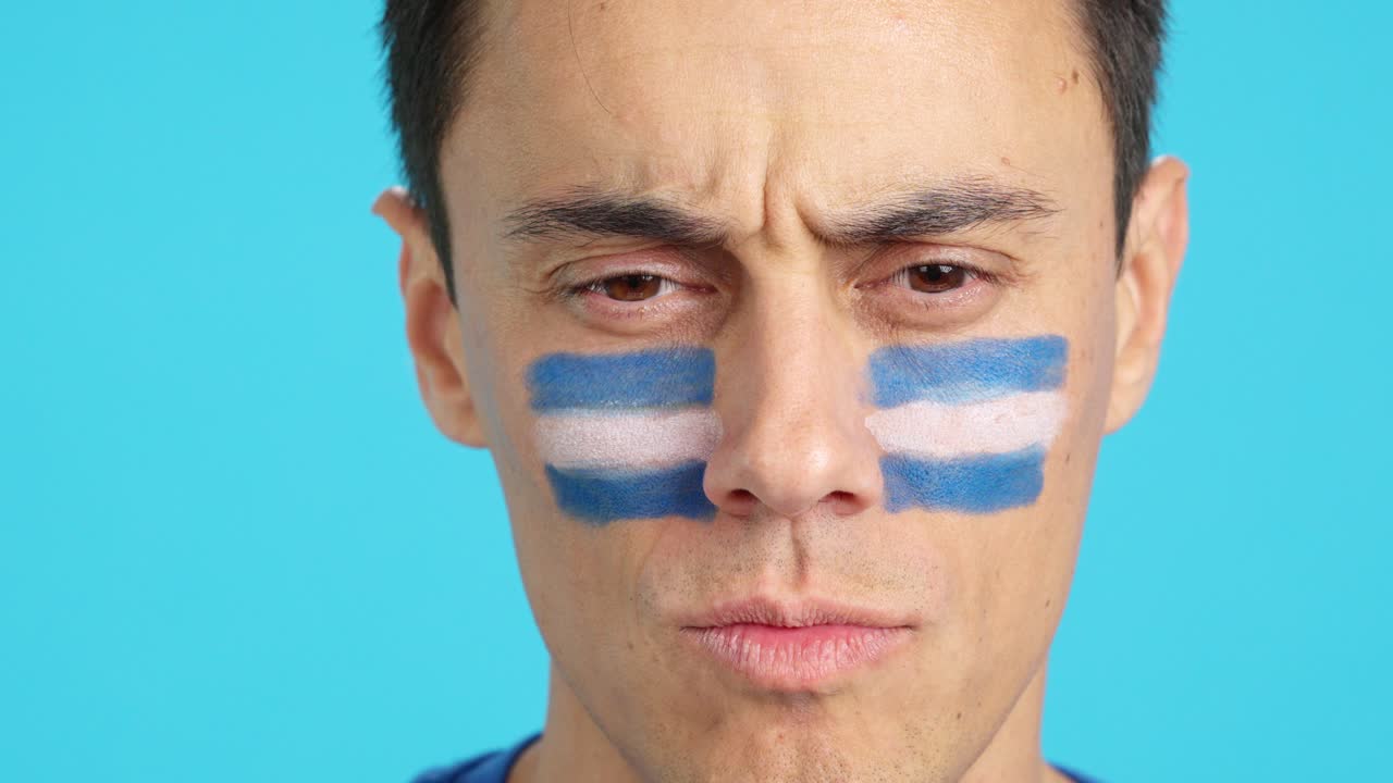 Serious man with a salvadoran flag painted on the face