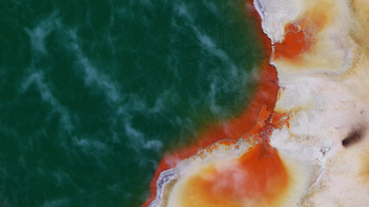Champagne Pool, Rotorua, Bay of Plenty, Nuova Zelanda, primo piano aereo di acqua geotermica color smeraldo, depositi minerali arancioni, superficie termale fumante e paesaggio vulcanico.