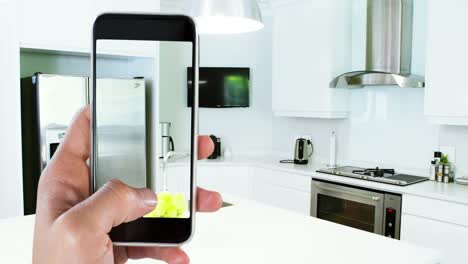 persona que sostiene un teléfono inteligente con interiores de cocina modernos mostrados en la pantalla